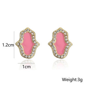 Detalle macro de pendientes de mano Hamsa chapados en oro con esmalte rosa y circonitas