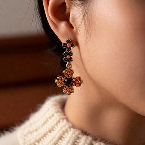 Detail of vintage gold earrings with orange zircons in a cross flower design