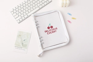 Flat lay of transparent PVC binder with cherry motif, keyboard and stylish desk decor