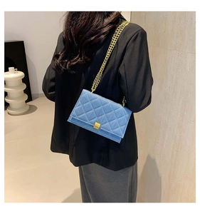 Detail of light blue quilted chain bag with gold hardware and secure twist-lock closure