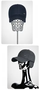 Detail view of winter baseball cap with ear flaps and metallic emblem in navy and grey