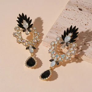 Detail of vintage palace style gold earrings with black teardrop crystal and opal stones