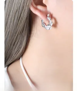 Close-up of a silver twisted rope hoop earring on model showing modern metallic texture