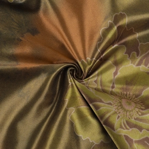 Detailed macro view of floral satin fabric with golden-brown and olive-green artistic prints