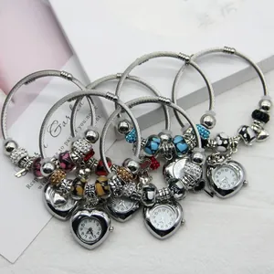 Detail of silver heart charm watch and decorative beaded bracelets with crystal accents