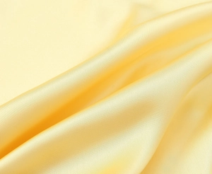 Gros plan sur le tissu jaune vif en mélange de ramie avec texture satinée et drapée