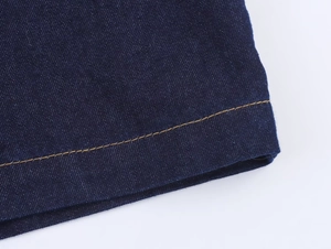 Makro-Detail von dunkelblauem Denim-Stoff mit gelben Kontrastnähten und Twill-Textur