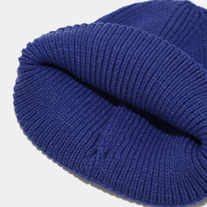 Macro shot of deep blue rib-knit pattern showing thick texture and warm embroidery detail