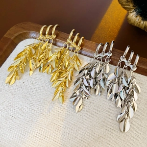 Detail of gold and silver wheat-shaped tassel earrings on a textured fabric tray