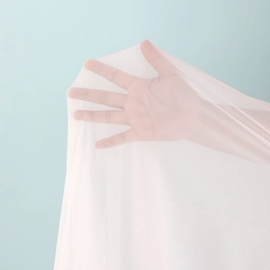 Detailed macro view of white sheer mesh fabric texture with fine breathable grid pattern
