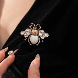 Detail of a vintage honey bee brooch with white stone and crystals on black fabric