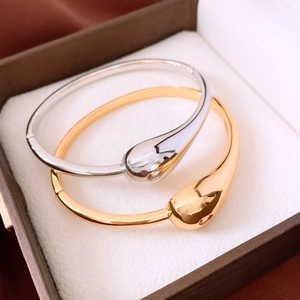 Close-up of gold and silver teardrop bangles with polished finish in a luxury jewelry box