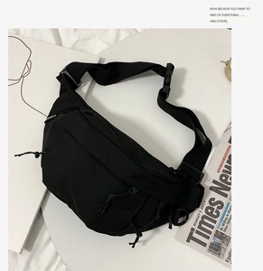 Detail of black nylon chest bag with adjustable strap and plastic buckle on white table