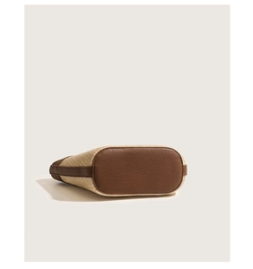 Detail of reinforced oval dark brown leather base on beige woven straw handbag