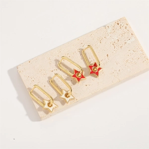 Classic star pendant earrings in gold with red and white enamel on a stone tray