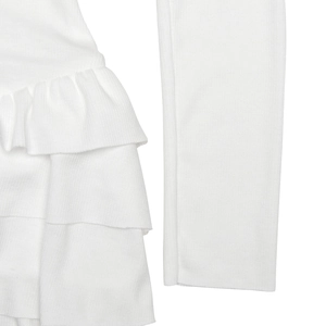 Detailed close-up of white ribbed knit fabric featuring elegant stacked ruffle hem and long sleeves