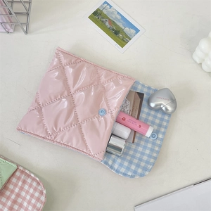Detail of pink quilted patent leather sanitary pouch with blue checkered lining and snap