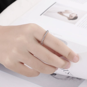 Détail d'une bague à perles argentées portée à la main sur fond de magazine épuré