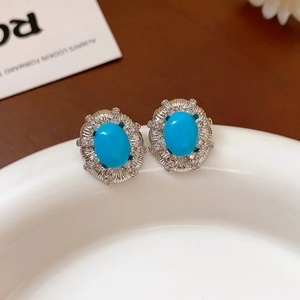 Dettaglio di orecchini vintage con pietra blu e base argentata su bordo in ceramica