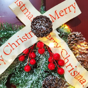 Detail of Christmas wreath with Merry Christmas bow, pine cone, berries and LED lights
