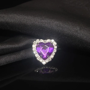 Macro view of purple heart-shaped crystal with white rhinestone halo on black silk