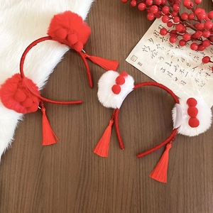 Detail of red plush hairbands with festive tassels and pom-poms on white fur background
