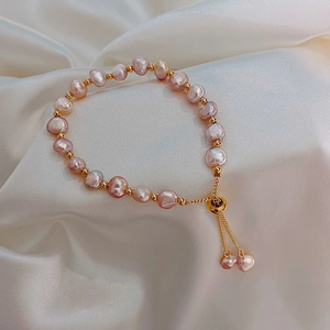 Macro detail of baroque pink freshwater pearls with gold spacers on white silk
