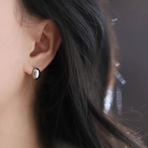 Macro shot of polished silver bean-shaped stud earrings showing high metallic luster