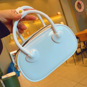 Close-up of white PVC jelly bag showing golden metal zipper and smooth glossy texture
