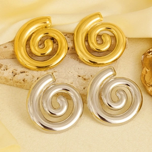 Detailed view of large gold and silver spiral shell earrings on minimalist stone base