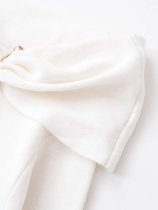 Close-up of white ribbed knit fabric with stylish knot design and gold metal fastener