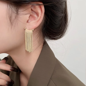 Close-up of elegant gold tassel earrings worn by a model in formal attire