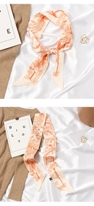 Macro detail of beige and orange silk scarf with H letter pattern on white fabric