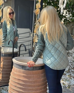 Detailed view of light green quilted puffer vest showing diamond pattern and zip texture