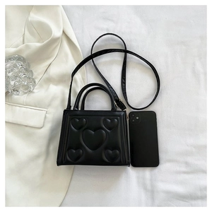 Détail d'un sac à main noir en cuir PU avec motif cœur gaufré et bandoulière amovible