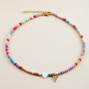 Detailed view of colorful beaded necklace with golden V pendant and white heart charm