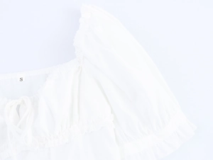 Detail eines weißen Kleides mit quadratischem Ausschnitt, Puffärmeln und Schnürung