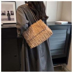 Detailed shot of beige woven shoulder bag with fringe pattern and gold chain strap