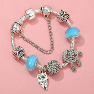 Detail view of silver snake chain bracelet with blue glass beads and owl charms