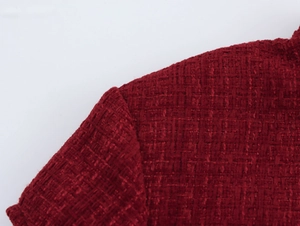 Gros plan détaillé montrant le tissage et la texture élégante de la robe en tweed rouge foncé