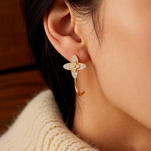Close-up of vintage C-shaped floral earrings with zircon stones worn by a model