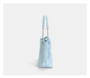 Detailed side view of light blue denim tote with cloud pattern and silver chain strap