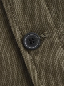 Close-up of olive green twill fabric showing reinforced stitching and black resin buttons