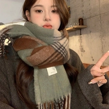 Detailed view of green and beige plaid scarf with fringes and soft woven texture