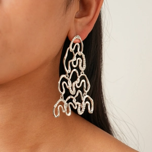 Macro view of silver geometric earrings with rhinestones shown on model ear
