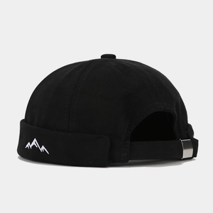 Detail of mountain embroidery and adjustable metal buckle on a black docker cap