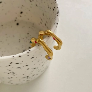 Irregular gold wave earrings with colorful rhinestones on white ceramic cup edge