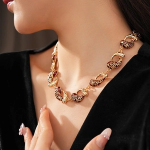 Close-up of golden necklace with red enamel floral pattern and sparkling zircon detail