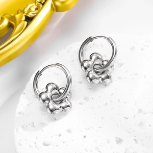 Detail of silver metallic hoop earrings with 3D five-petal flower charms on white display