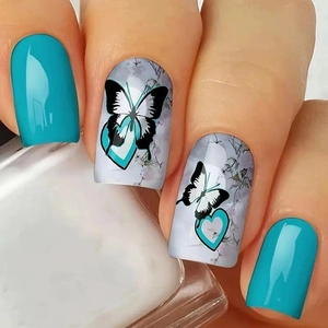 Close-up of green press-on nails featuring butterfly and floral patterns with glossy finish